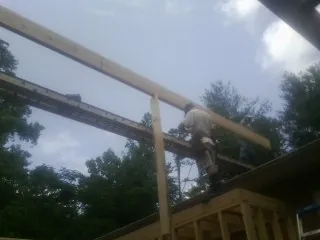Carpenter setting a ridge beam over a new addition frame in Oelwein