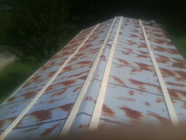 Rusted metal roof panels with new wood purlins before replacement — Storm Damage Roof Repair in Oelwein by Roofing Brothers