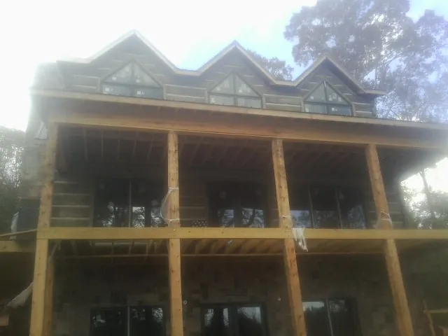 Dormers and porch framing on a large log home under construction — Roof Coating work by our crew in Oelwein