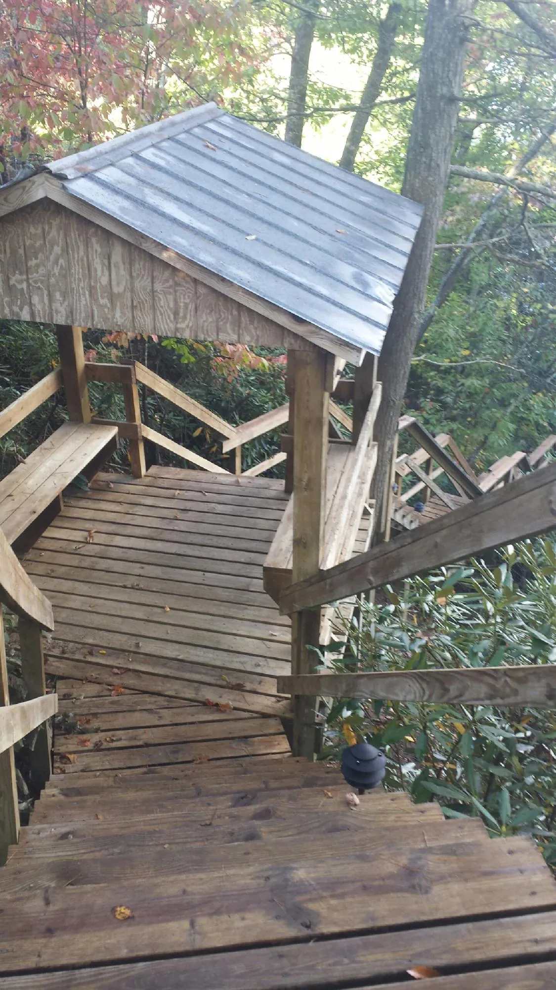 Metal roofed shelter over wooden steps on a wooded walkway — Skylight Repair & Installation work by our crew in Oelwein