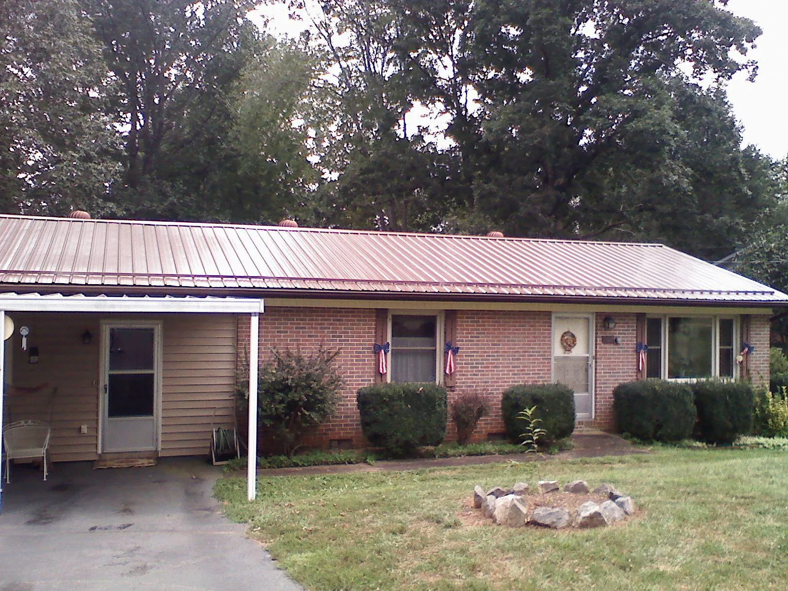 Bronze metal roof and carport on a brick ranch home — Roof Repair work by our crew in Oelwein